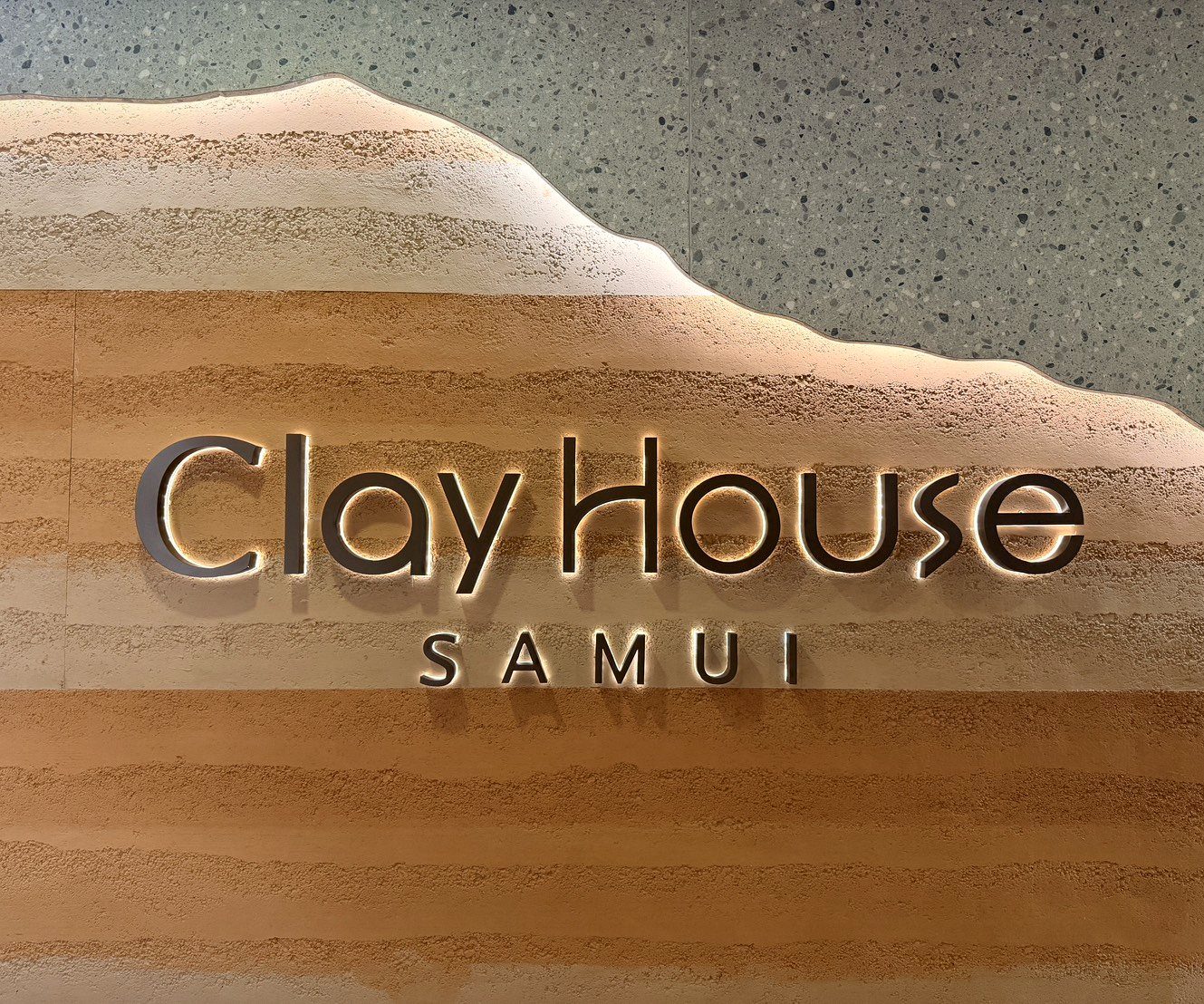 ป้าย ClayHouse SAMUI บนผนังดินที่ฝ่ายบริการผู้เข้าพัก